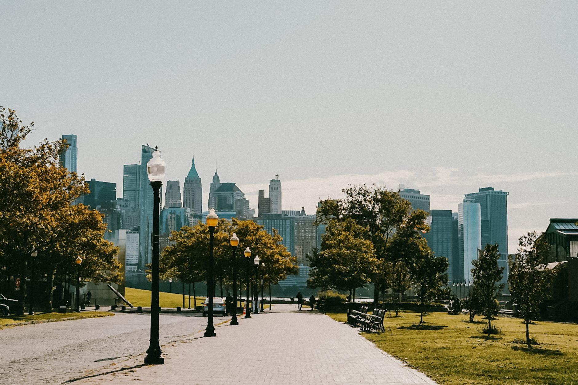 A serene city park with a scenic view of an urban skyline and green trees on a sunny day.