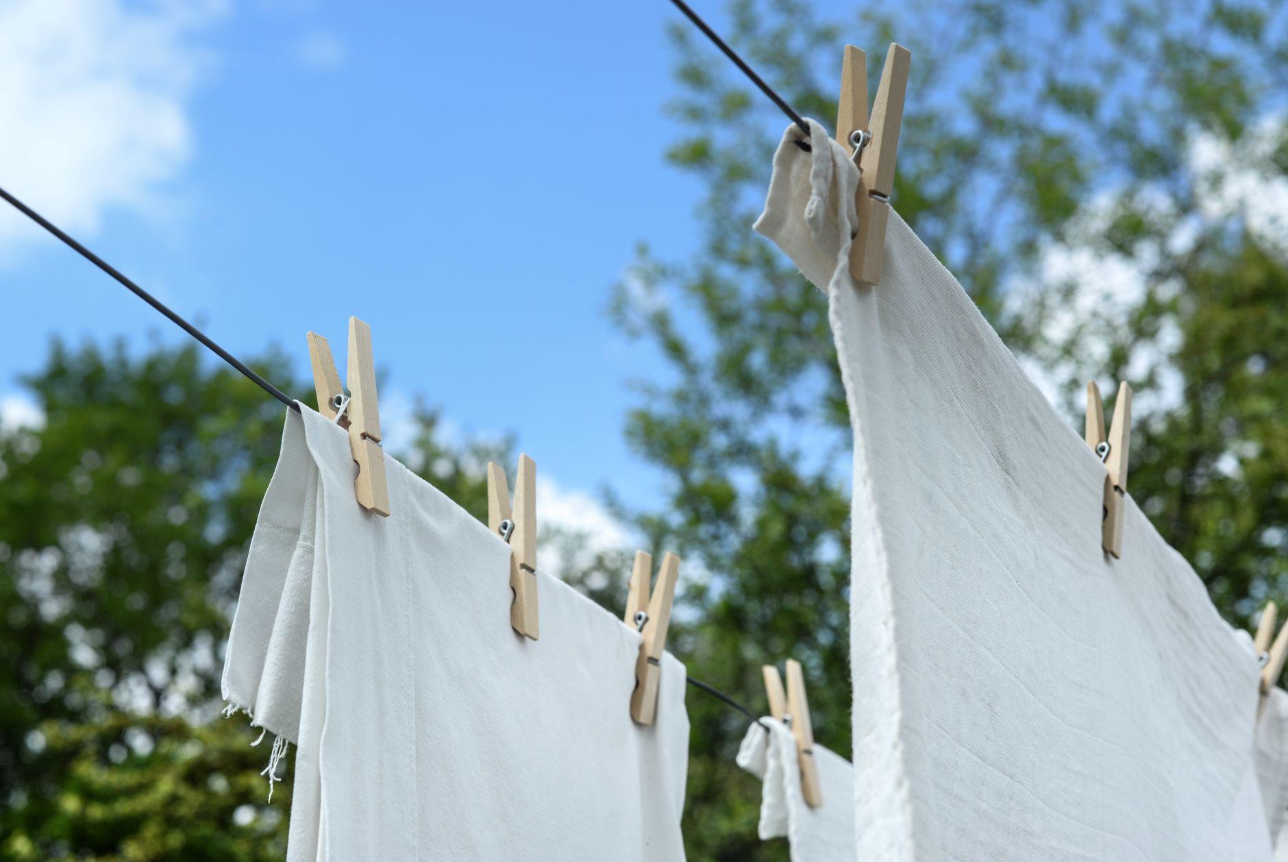 Close-up of white laundry drying on a clothesline under a clear blue sky.
