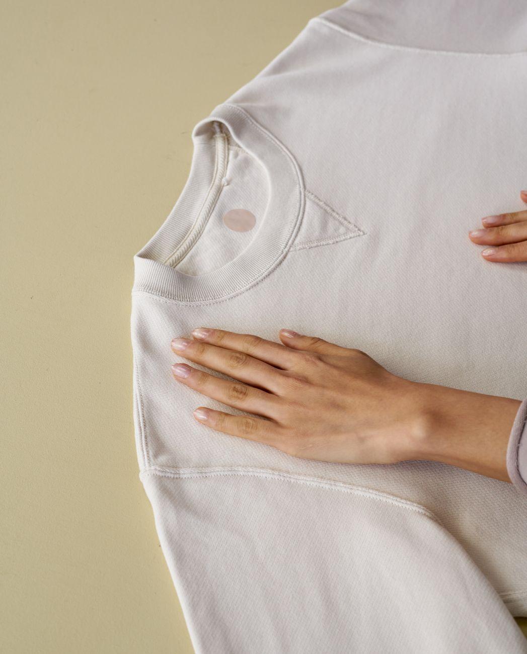 Close-up of hand gently placed on a white sweater, emphasizing fabric care.