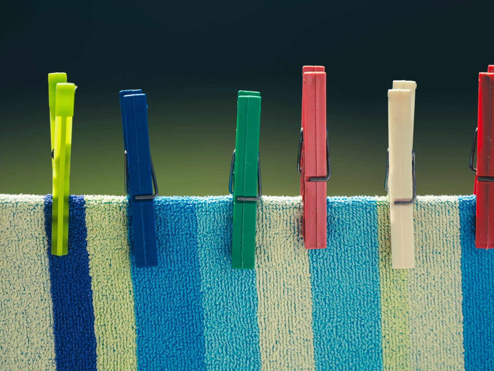 Brightly colored clothespins secured on a striped towel in the sun, perfect for lifestyle themes.