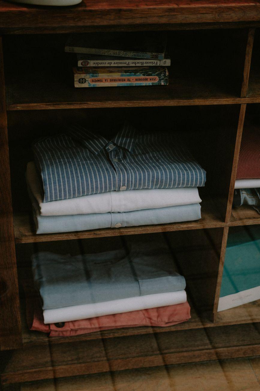 A tidy wooden shelf with neatly folded clothes and stacked books.
