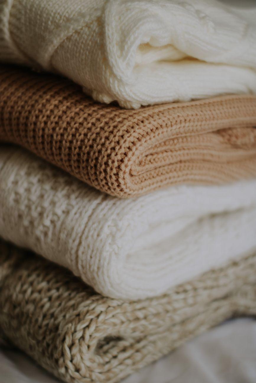 Pile of beige and cream knitted blankets folded neatly for warmth and style.