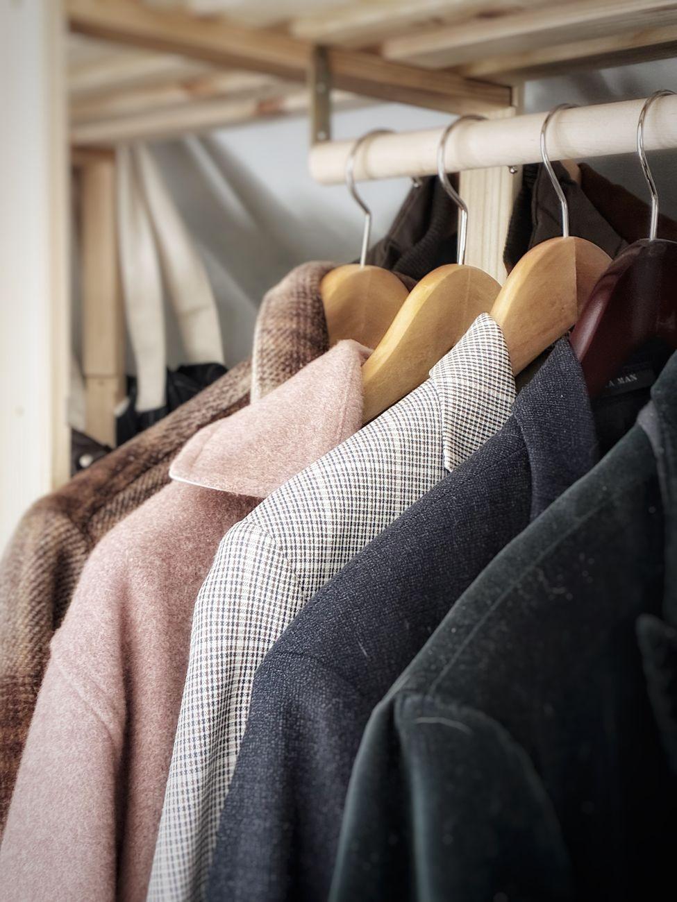 A collection of stylish coats hanging in a wardrobe, showcasing different fabrics and textures.