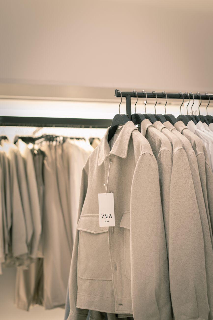 Stylish beige coats neatly arranged on racks in a modern clothing store interior.