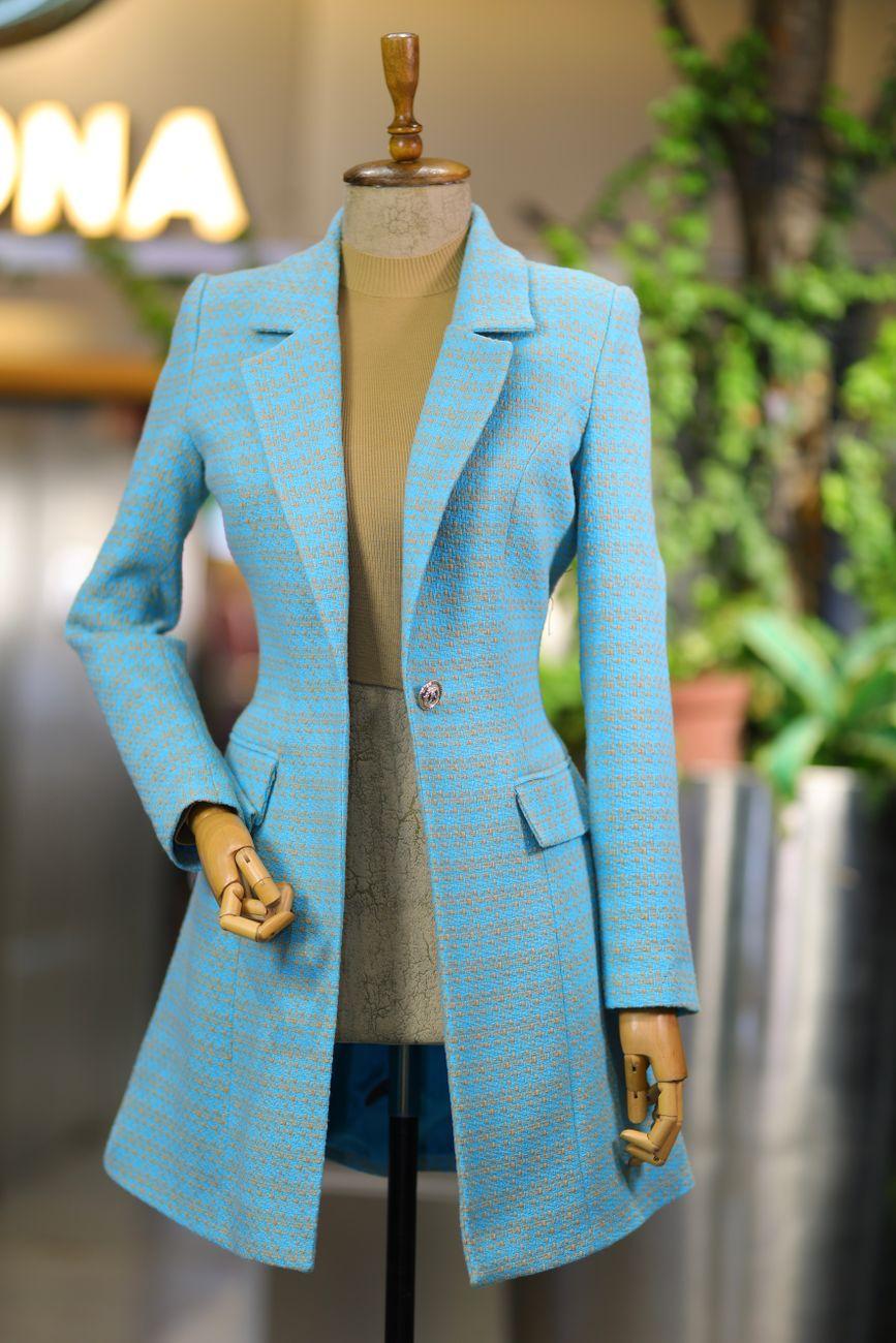 Elegant blue coat draped on a mannequin in an indoor fashion display setting.