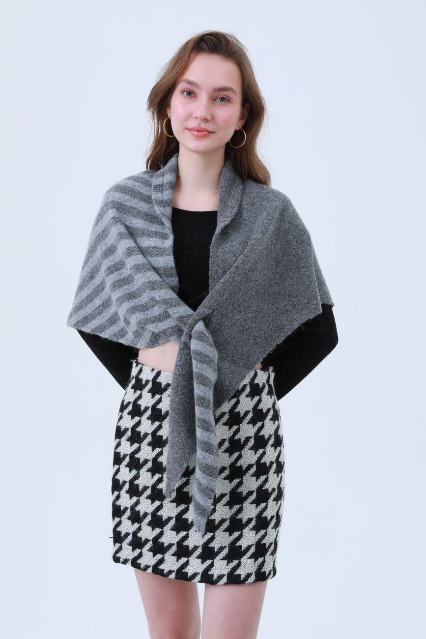 Stylish adult woman in gray shawl and houndstooth skirt posing indoors.