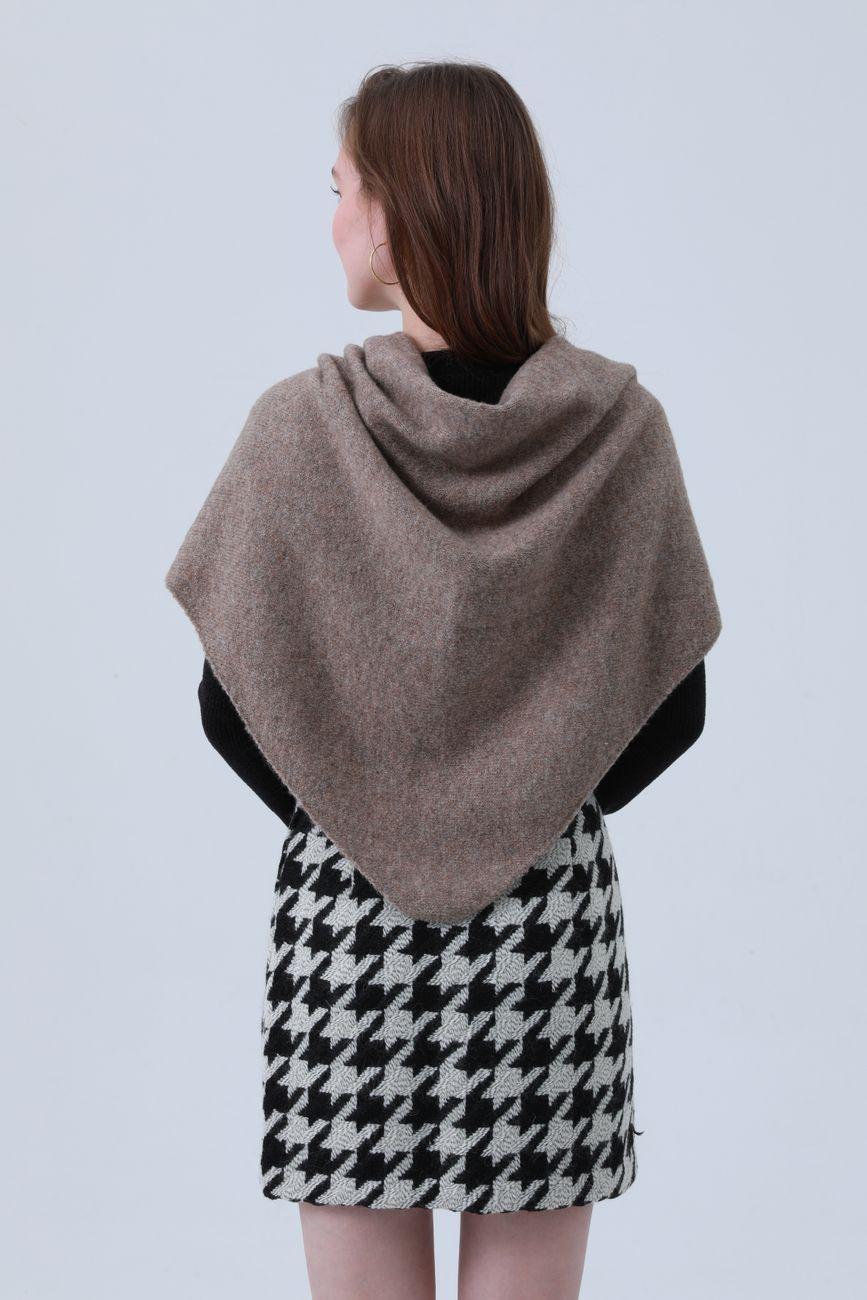 Woman wearing a brown shawl and houndstooth skirt from behind.