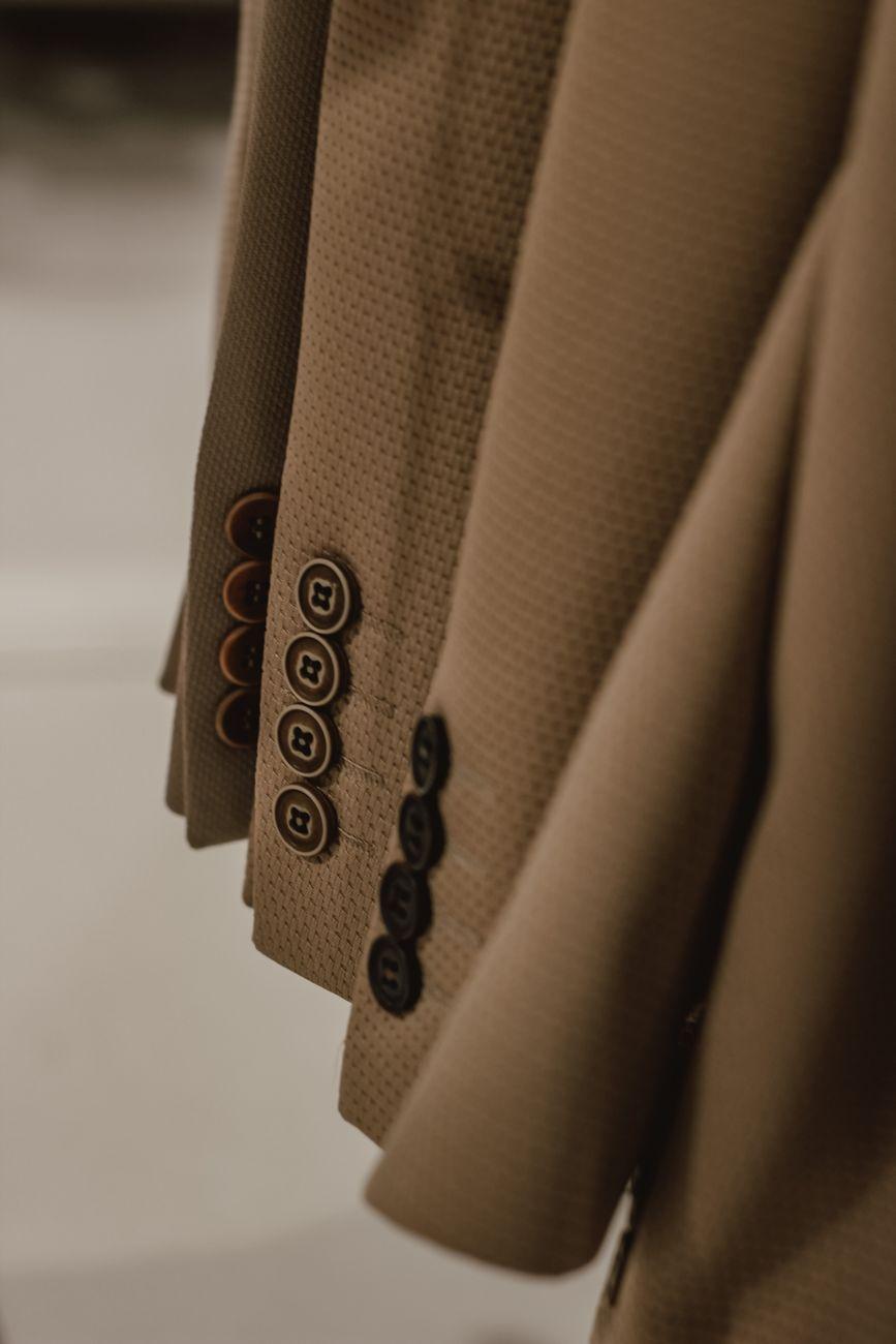 Detailed close-up of beige blazers with button design hanging on a rack.