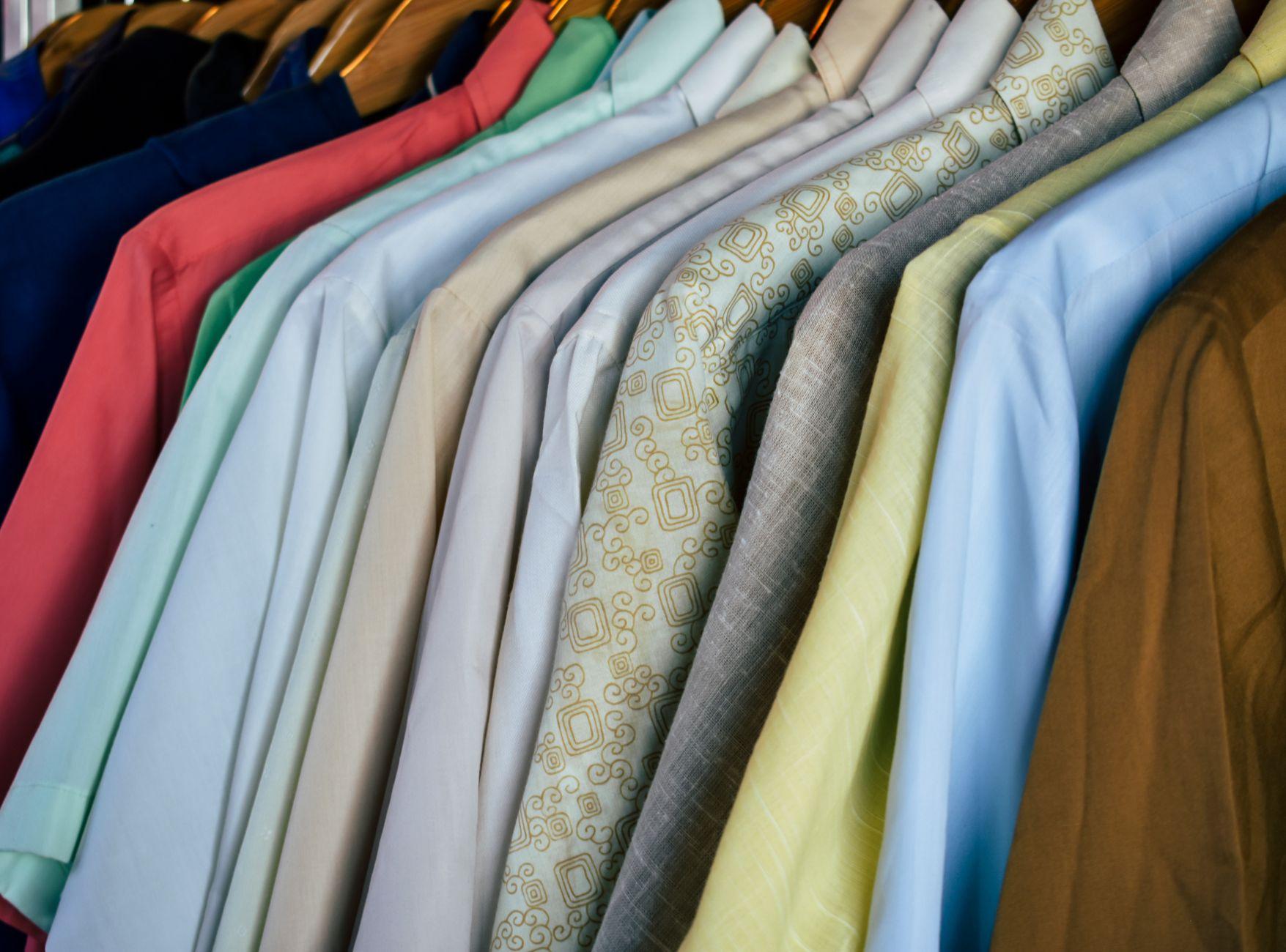 A variety of colorful shirts neatly hung on wooden hangers, showcasing diverse fabrics.